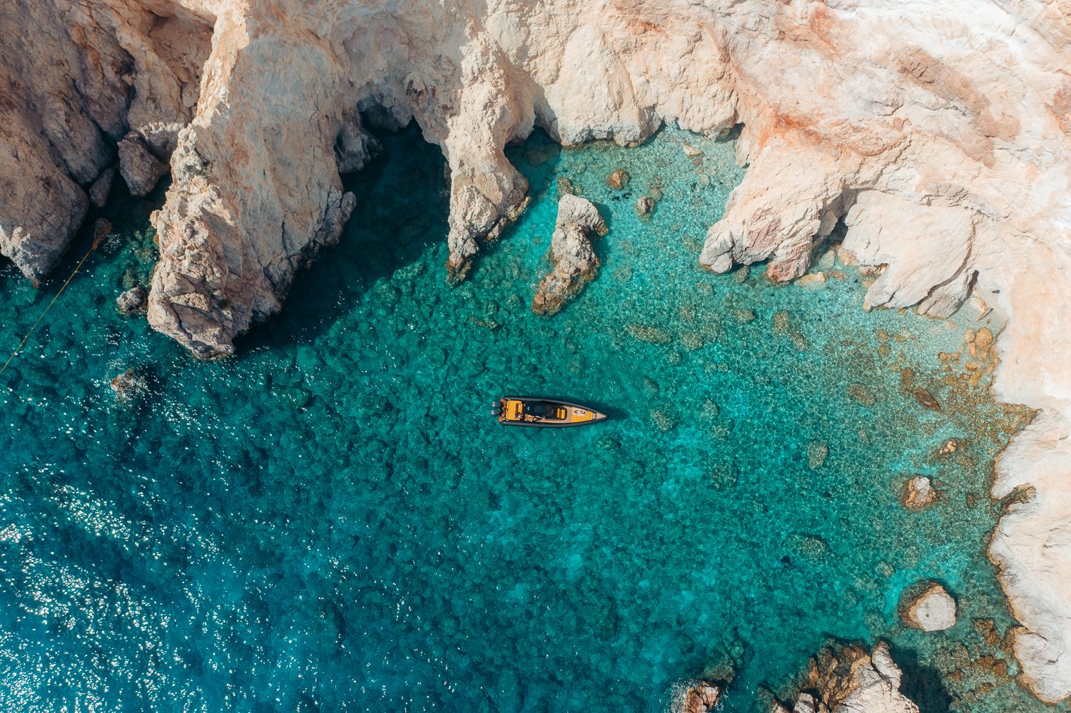 Aerial view of a Technohull boat in a turquoise rocky cove