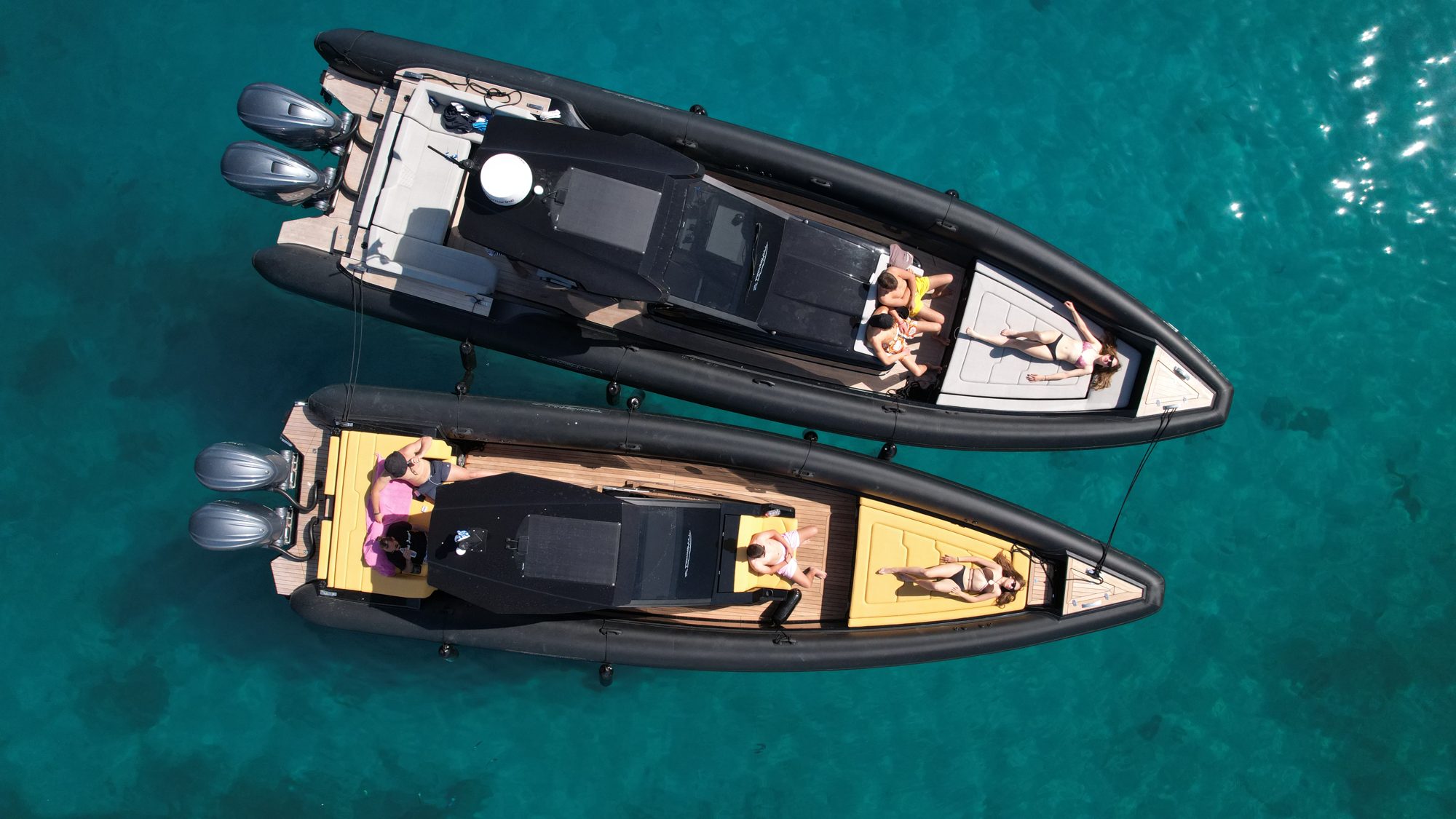 Two Technohull boats with guests on deck in clear water