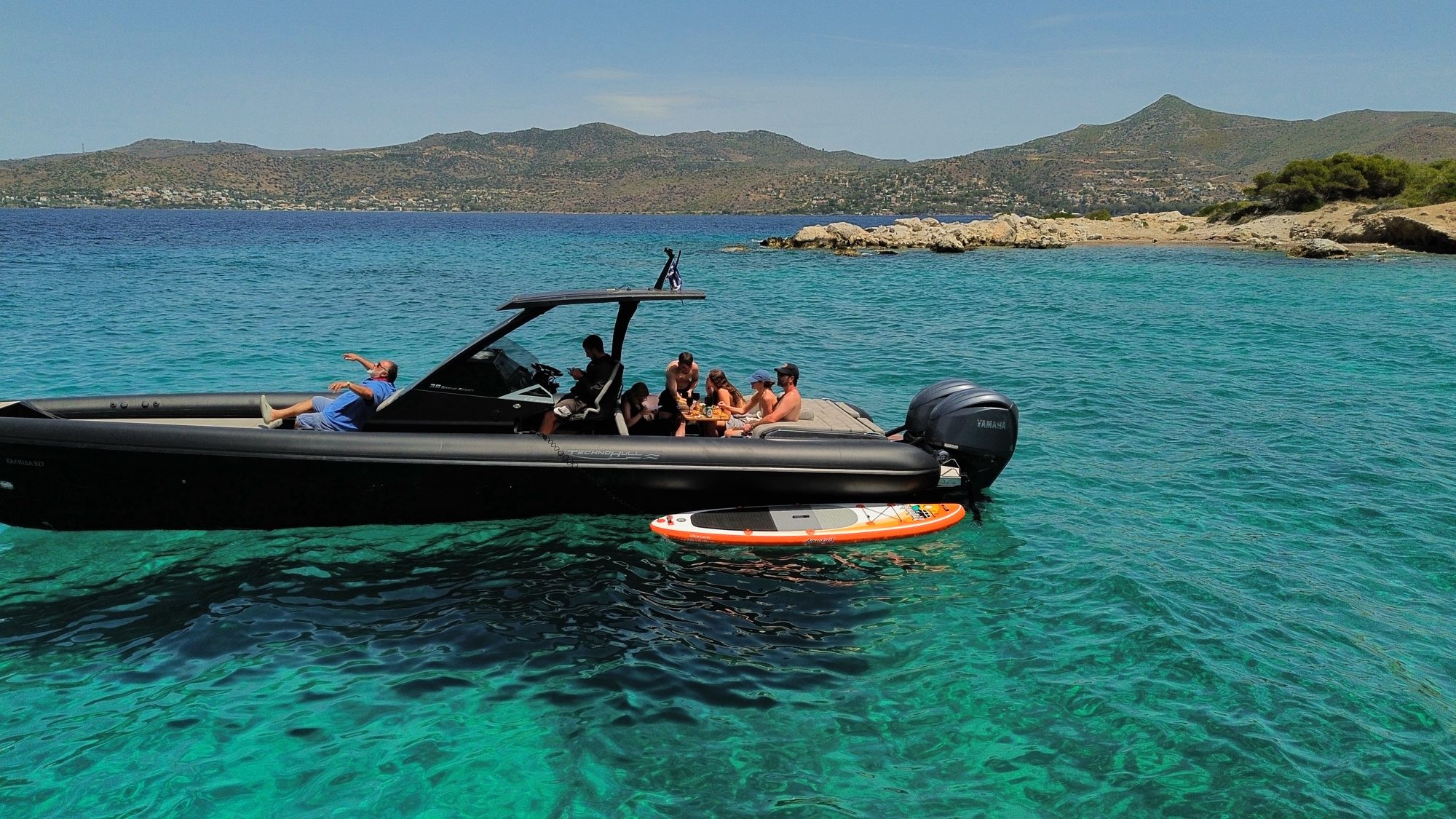 Guests sharing lunch aboard a Technohull boat in a sheltered bay