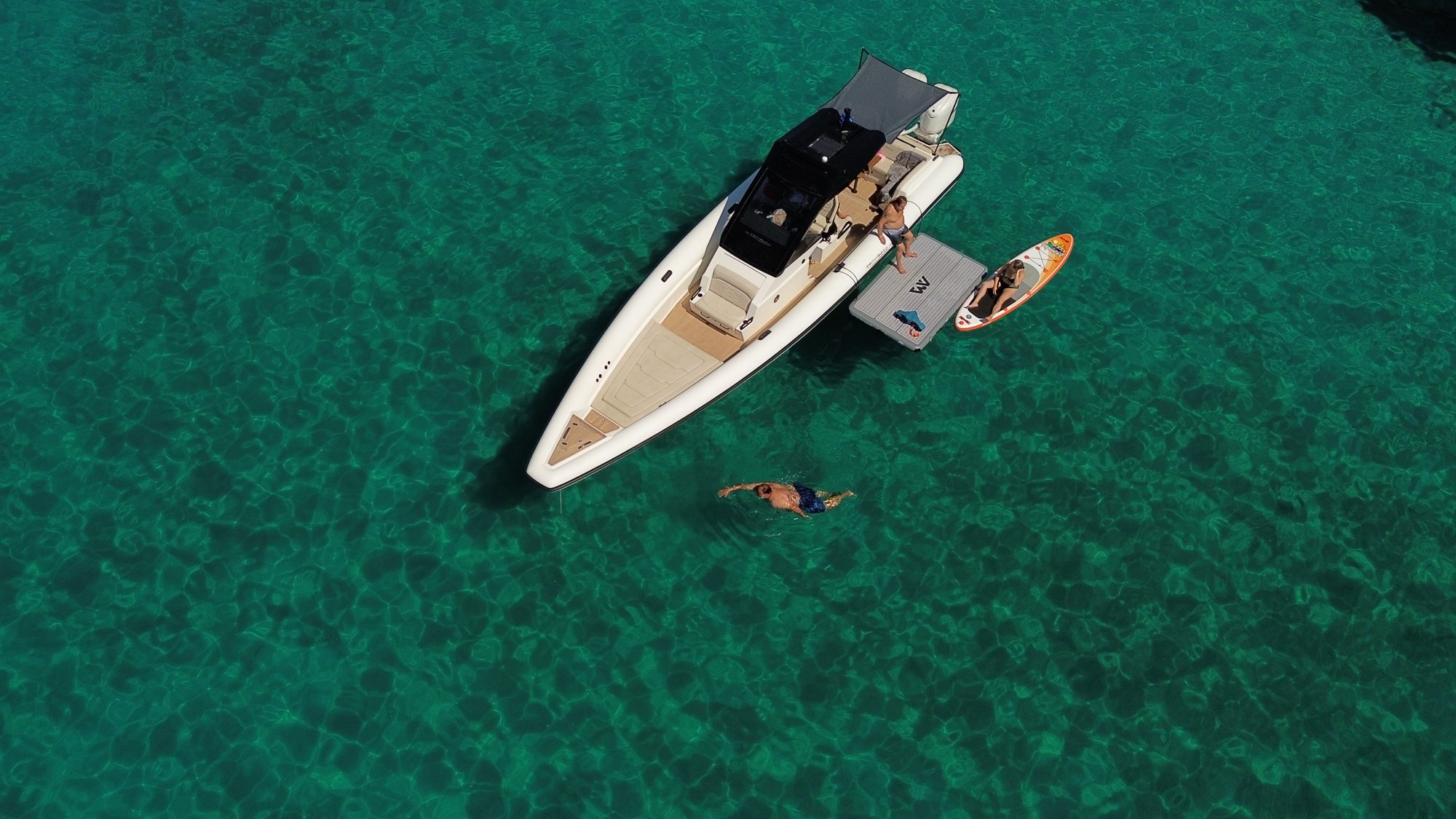 Guests swimming beside a Technohull boat in clear water