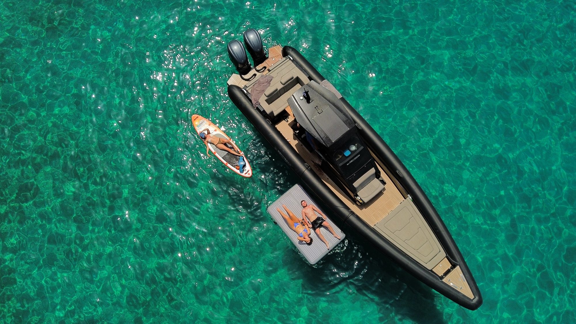 Technohull boat with paddleboard and floating platform in clear water